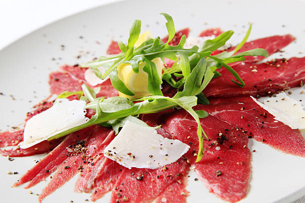 Close-up of carpaccio on white plate Slices of Carpaccio and Parmesan carpaccio parmesan cheese beef raw stock pictures, royalty-free photos & images