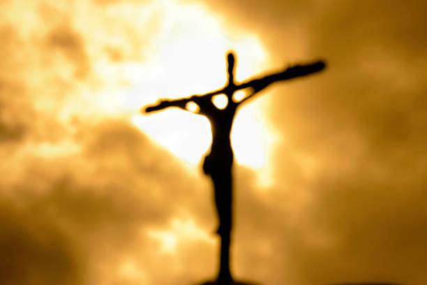 Cross against a dark yet bright sky symbolizing forgiveness Defocused figure of Crucifixion cross shape stock pictures, royalty-free photos & images