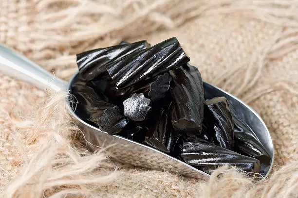 A scoop of old fashioned black liquorice candy on frayed burlap.