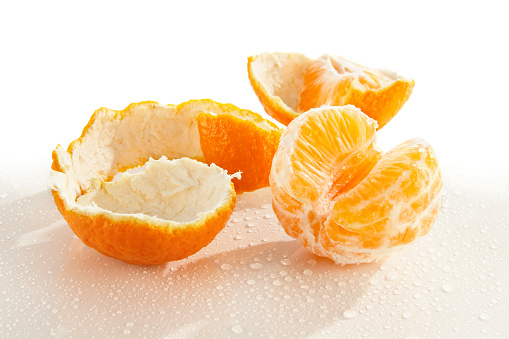 A partially peeled clementine on white... a perfect healthy snack.