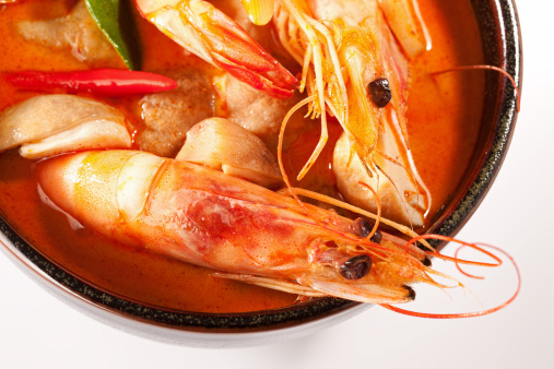 Spicy Thai Prawn soup (Tom Yam Kung). This famous Thai dish is very spicy and made with lemon grass, kaffir lime leaves, galangal and chili. Here it is photographed in a traditional terracotta soup bowl.