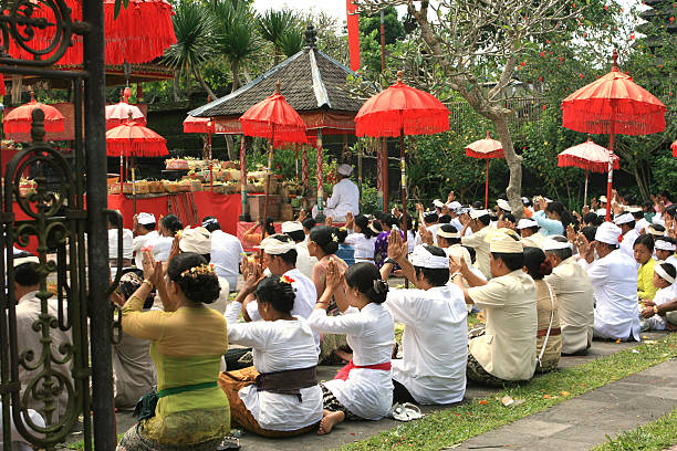 Horizontal closeup photo of a Balinese woman kneeling in the temple with her hands together in prayer position praying in the Central Market temple in Ubud, Bali. Jalan Raya, Ubud, Bali, Indonesia