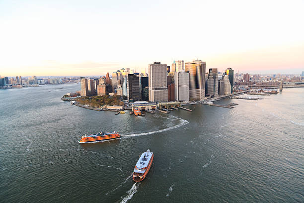 New York. USA. 09.25.2023. Beautiful landscape view of sightseeing cruise boats navigating along Hudson River past skyscrapers of Manhattan, with iconic Brooklyn Bridge in background.