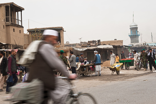 Kabul, Afghanistan - November, 7 2008: \nAn Afghan man riding his bicycle through Kabul Bazar