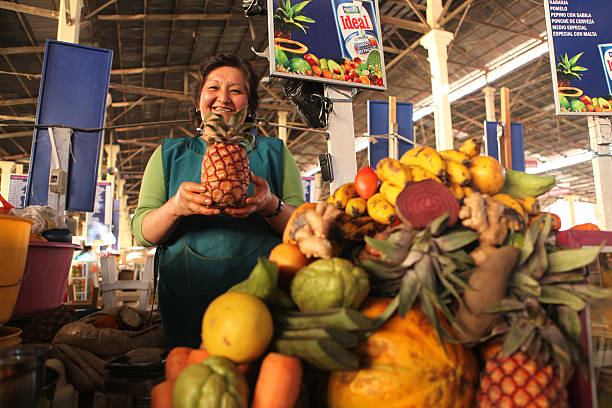 A pineapple and a few of peaches on the shelf at the grocery.