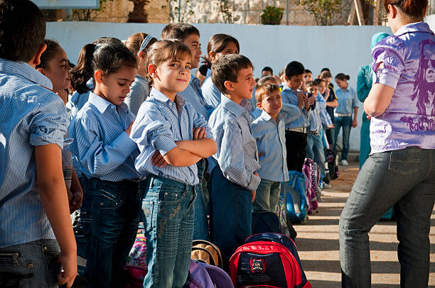 Aboud, West Bank, Palestinian Territories - October 25, 2010: Elementary-aged boys and girls line up in a school courtyard for the national anthem and the start of another school day. This particular school is operated by the Latin Patriarchate (based in Jerusalem) and counts both Muslim and Christian Palestinians among its students. Several towns and villages in the West Bank have Catholic schools.