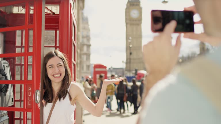 Tourist couple taking photograph of each other while sightseeing making funny faces enjoying European summer holiday travel vacation adventure