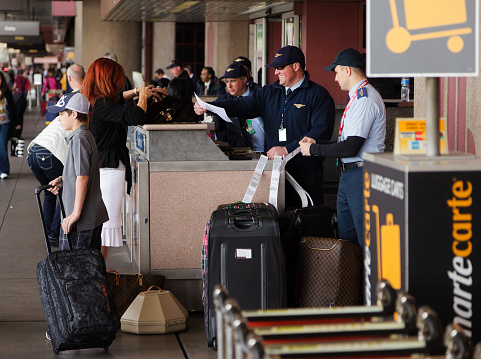 Las Vegas, Nevada, USA - March, 1 2011: A sky cap employee of TGS Aviation Services assists a woman traveler with her curbside baggage check-in at McCarran International Airport in Las Vegas, Nevada.