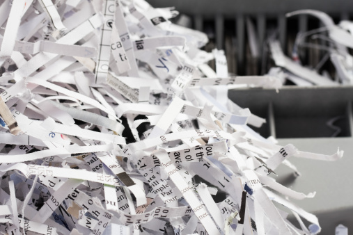 Destroyed corporate office documents, cut into strips of paper in a shredder closeup