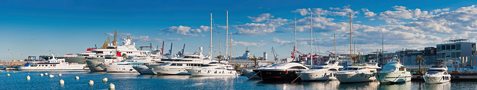 Valencia, Spain - February 20th, 2011: The luxury yachts and motor boats moored in the port of Valencia, home to the America's Cup teams in 2007 and 2010. Composite panoramic image created from twelve contemporaneous sequential photographs.