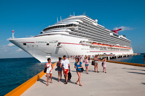 Summer of 2015- the beautiful Carnival Breeze cruise ship sits in the beautiful blue Caribbean waters of Grand Cayman while tenders bring passengers to land.