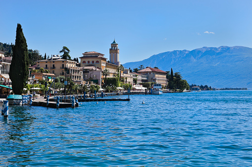 Gardone Riviera, Lombardy, Italy  - June 1, 2010: A ferry is leaving from the little harbor of Gardone Riviera. The historic centre and the beautiful lakeside of this enchanting city are a succession of villas and hotels surrounded by parks that still preserve the liberty style of the late 19th century.