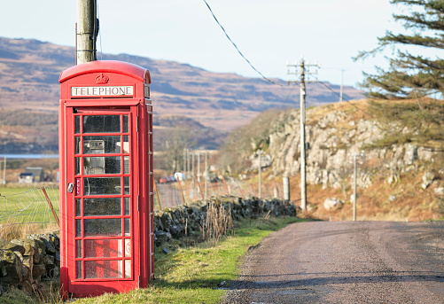 A photograph of a Red Telephone Kiosk outside the rural Entwistle Railway Station in Lancashire, England. The Railway Station serves the East Lancashire Railway Line. The photograph was produced on a bright but cloudy day with light rainfall.