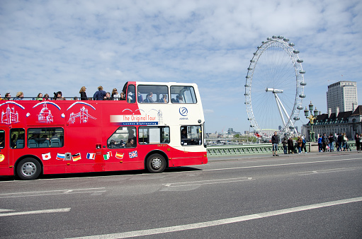 London, UK - Aug 19, 2021: Group of tourists on the the excursion in open top bus in London. Open top buses are used in the United Kingdom for sightseeing and seasonal summer services