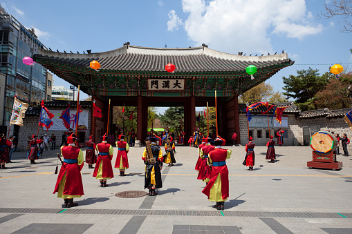SEOUL, SOUTH KOREA - April 24, 2011: Men dressed in Red and Yellow traditional costume line up as part of a Changing the guards ceremony with Deoksugung Palace entrance in the background, Seoul, South Korea