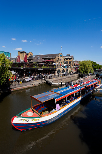 London, England - May 2, 2011: Narrow canal Boat passes through the Camden Lock with Market buildings in the background