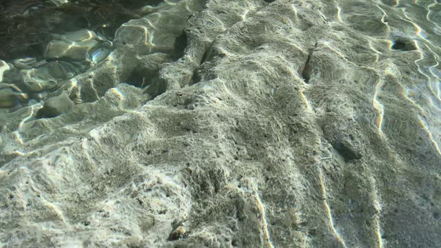 Crystal clear sea water with stones and pebbles at the bottom.