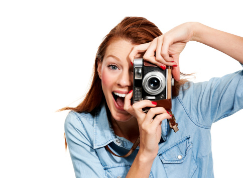 Portrait of a young woman laughing at you from behind a camera