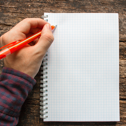 left-handed man writes in a notebook