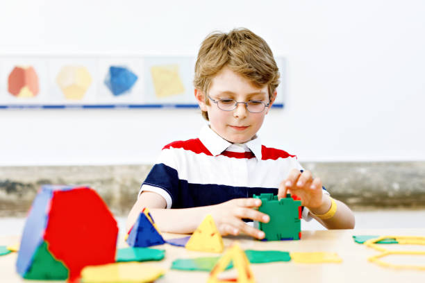 istock Happy kid boy with glasses having fun with building and creating geometric figures, learning mathematics and geometry 1577831960
