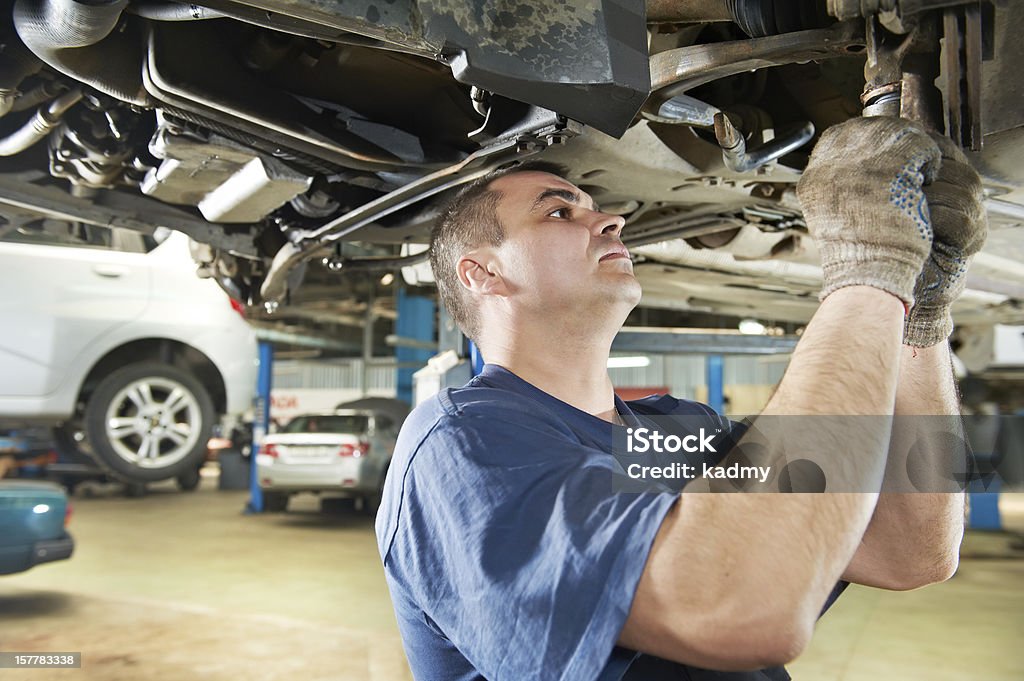 auto mechanic at car suspension repair work car mechanic examining car suspension of lifted automobile at repair service station Mechanic Stock Photo