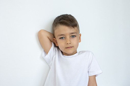 Portrait of a little boy on a white background. The child is wearing a white T-shirt.