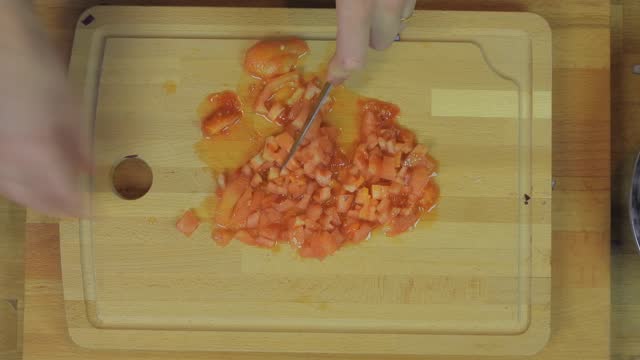 Woman Chopping Tomato at Wooden Kitchen Table