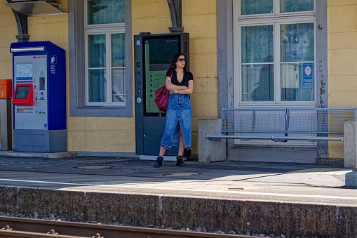 Travel by train. Woman waiting for train on foggy railway station. Female tourist standing at railroad platform