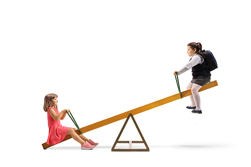Two girls playing on a seesaw isolated on white background