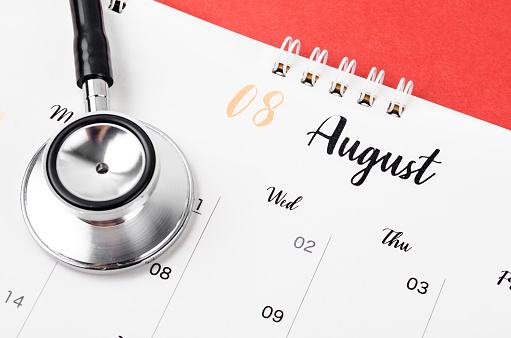 Stethoscope medical and August 2023 desk calendar on the red background, schedule to check up healthy concepts.