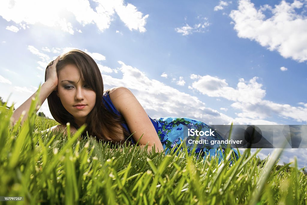 Beautiful Girl Lying in Grass Beautiful Girl Lying in Grass under a partly cloudy sky Adult Stock Photo