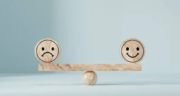 Photo of Happy and sad smiley faces on wooden seesaw. Customer satisfaction, evaluation or positive feedback concept.