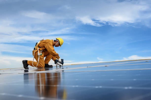 istock Technician Young Wearing Safety Protective Clothing on Walkway and Using Tool Installing Solar Panel or Photovoltaic at Support Point in Daytime on Factory Roof Buildings. 1577998392