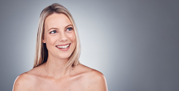 Woman, thinking and skincare aesthetic with mockup in a studio for wellness and cosmetics. Facial, smile and happy model with gray background and mock up ready for dermatology and self care treatment