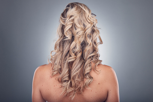 Hair care, beauty and woman with curly hairstyle texture after salon treatment in a studio. Gray background, isolated and model with hairdresser balayage, dye and growth from haircut and keratin