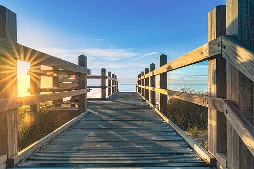 A wooden bridge spanning a sun-soaked sandy landscape