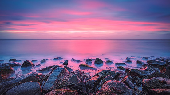 A picturesque pink sunset over a rocky shoreline