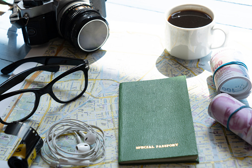 Travel concept flat lay table top shot on wooden background. Map, coffee, passport, glasses, earphones, camera and film rolls on the table