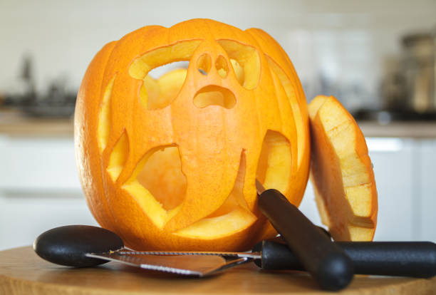 Halloween carved ghost pumpkin lantern. Creative Jack-o'-lantern pumpkins decorating ideas, scary spooky ghost cut out with carving tools - spoon or scoop gutter, saw knife blade carvers.