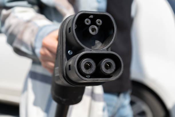 istock Woman holding CCS fast charging socket type 2 plug for electric vehicles at EV car charging station. 1578064195