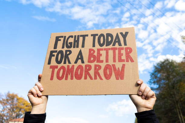 Woman holding placard sign with text Fight Today For a Better Tomorrow. Female protestor with cardboard banner at protest rally demonstration.