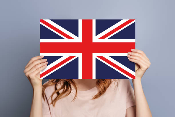 istock Student holds uk flag emblem speech bubble isolated over grey studio background 1578090316