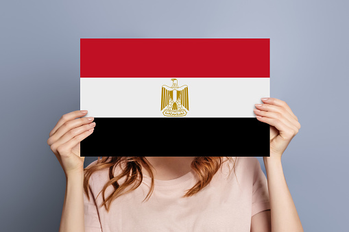 The national flag of Egypt with fabric texture waving in the wind on a blue sky. 3D Illustration