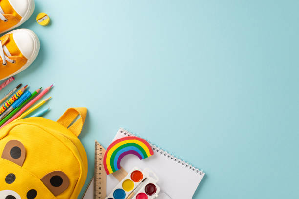 istock Educational beginnings. Top-down view of a bright kid's rucksack surrounded by an assortment of vivid school items and kid's gumshoe on a pastel blue backdrop, ample space for messages or ads 1578100618