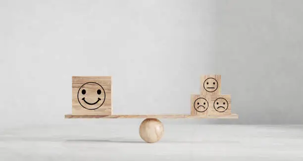 Photo of Happy and sad smiley faces on wooden seesaw. Customer satisfaction, evaluation or positive feedback concept.