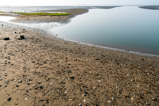 Beautiful empty beach on the coast of Lake Garda (Lago di Garda) near the small Garda town, Promontory or headland of San Vigilio (Punta San Vigilio), Verona province, Veneto, Italy, Europe. On the horizon, the coast of Lombardy on the right.