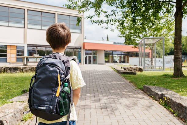 istock Back view of a boy with a backpack on his back going to school. Back to school. Beginning of the school year and school hours. 1578201928