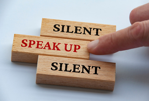 Finger pushing wooden block with red written text speak up. Courage and speak up concept.
