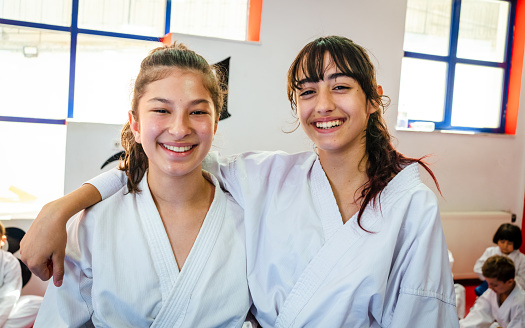 teenage girls hugging and smiling while learning taekwondo or karate