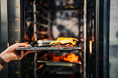 chef hand cooking cheese burger in oven on restaurant kitchen